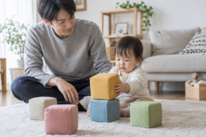 大きな布の積み木で遊ぶ1歳の子どもと見守る父親