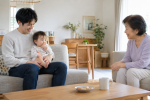 父親の膝で祖母を見つめる赤ちゃん